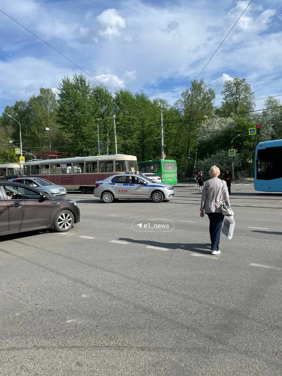 Автомобиль силовиков перегородил трамвайные пути в сторону центра — светофоры работают, но трамваи и автомобили встали в большую пробку; для координации движения выставили регулировщика.