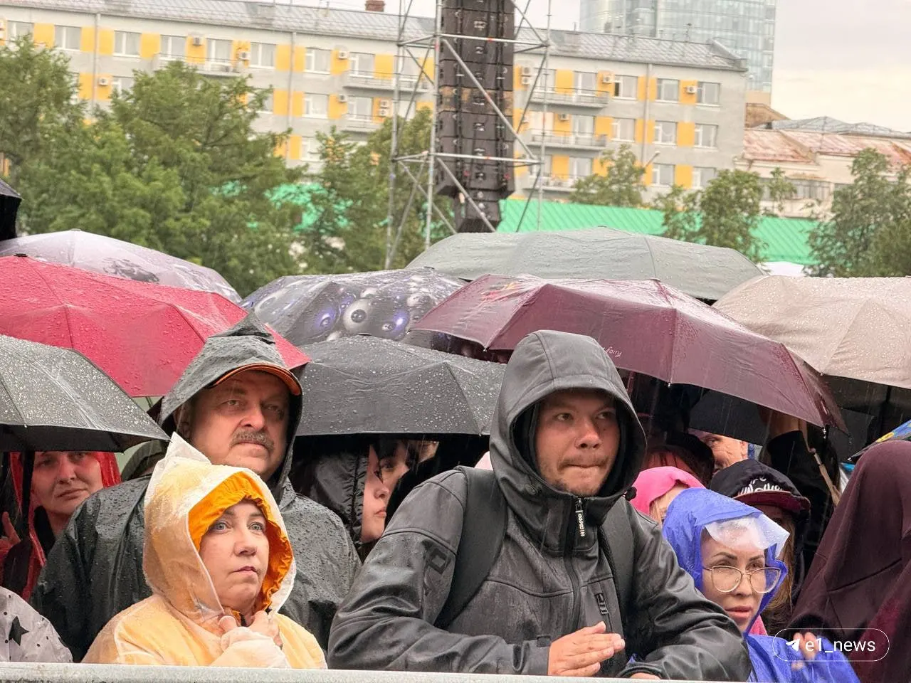 На концерте в Екатеринбурге сильный дождь заставил публику прятаться под зонтами и одеждой. Сергей Бобунец должен был выйти на сцену полчаса назад, но пока не появился — причина задержки неизвестна.
