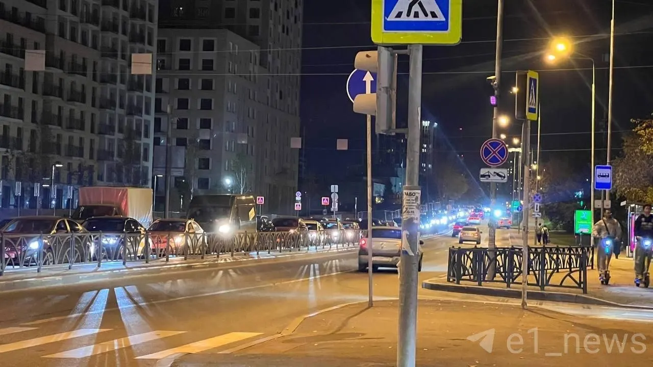 На перекрёстке Екатеринбурга сформировалась затяжная пробка; дежурит регулировщик, который подсказывает водителям, когда ехать и переходить дорогу.